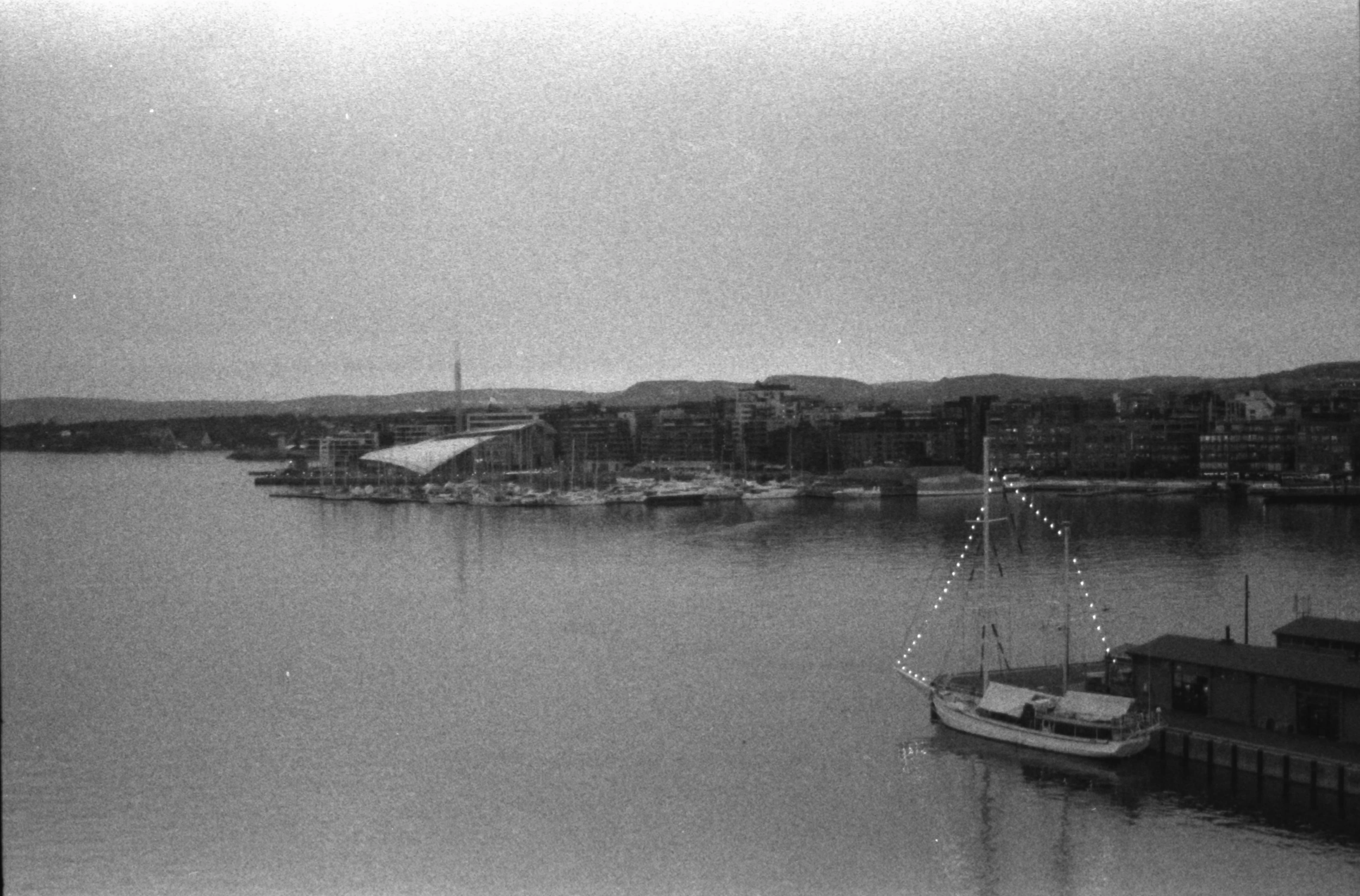 Black and white picture of Oslo’s coast featuring some boats and some obscure buildings