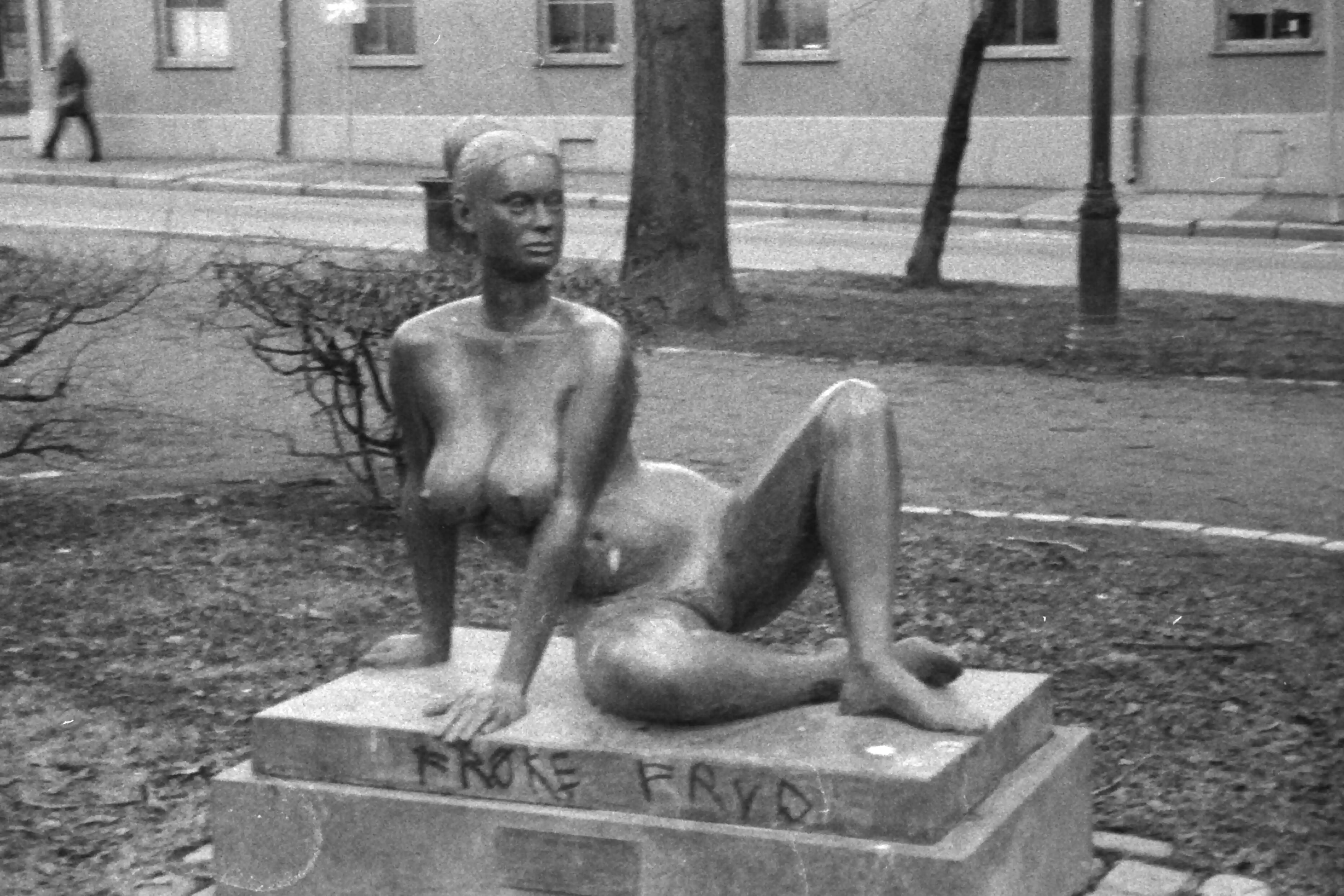Black and white picture of a naked statue of a woman laying down. The text “Frøke Fryd” is tagged on the foundation of the statue
