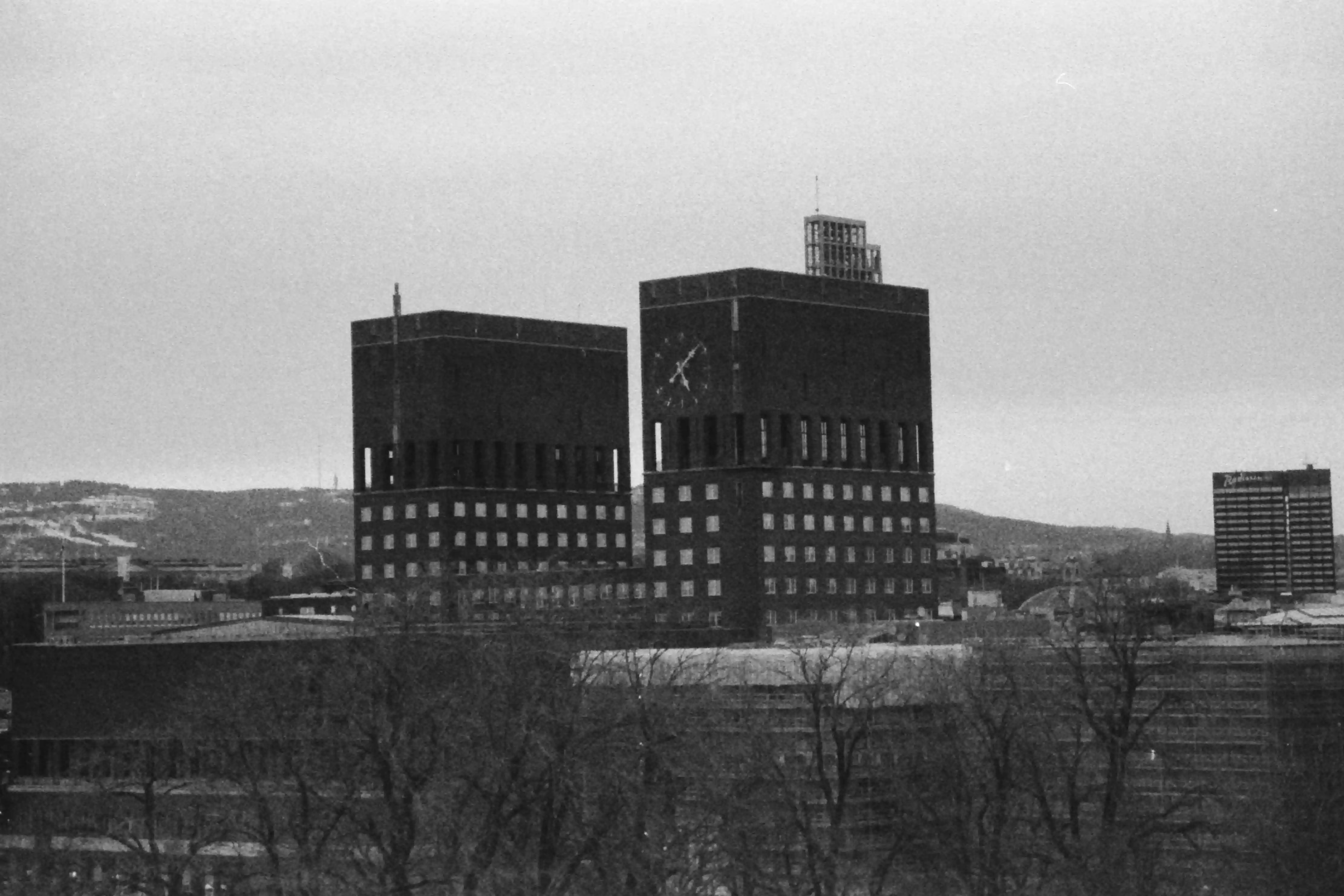 Black and white picture of Stortinget behind some barren trees.