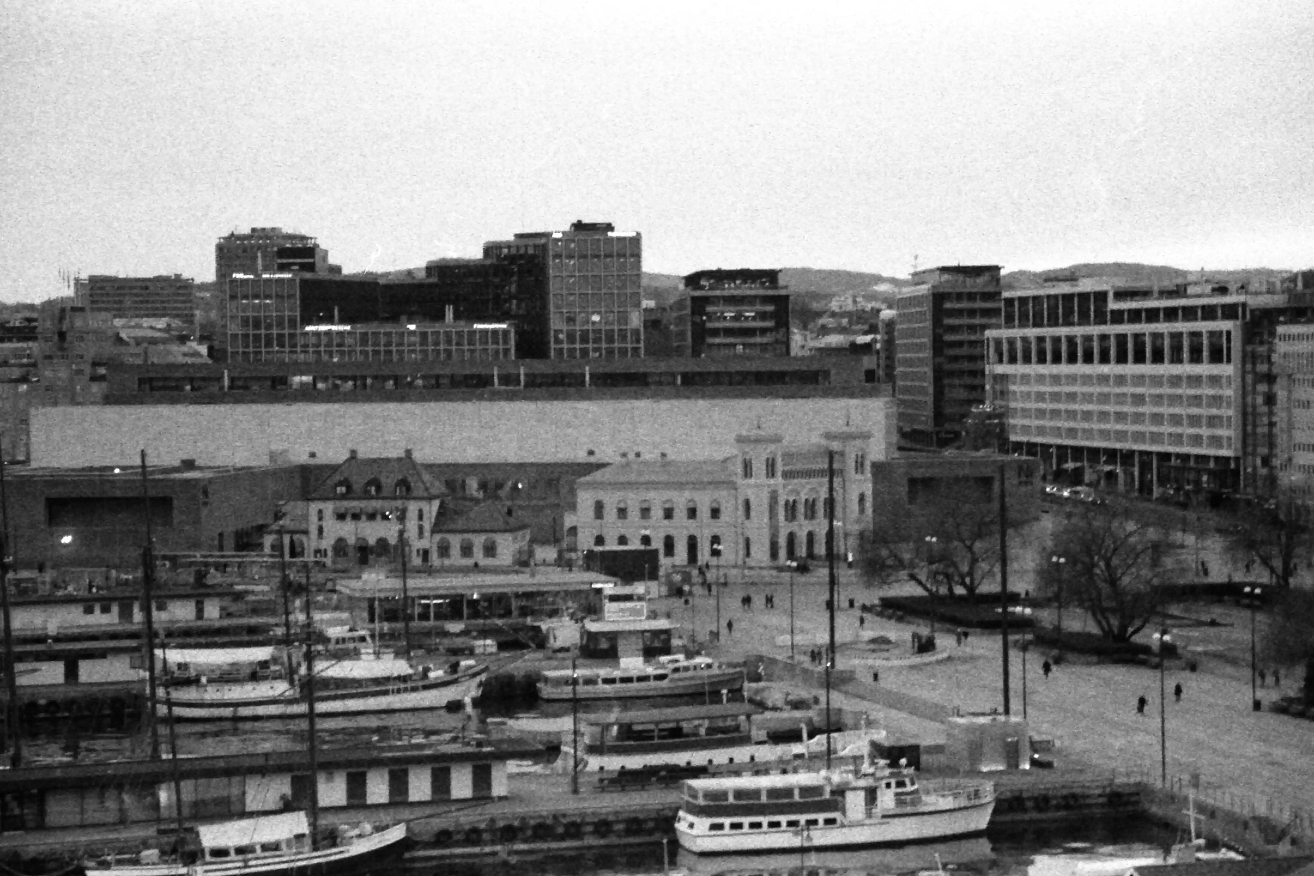 Black and white picture of a pier with some boats and some buildings