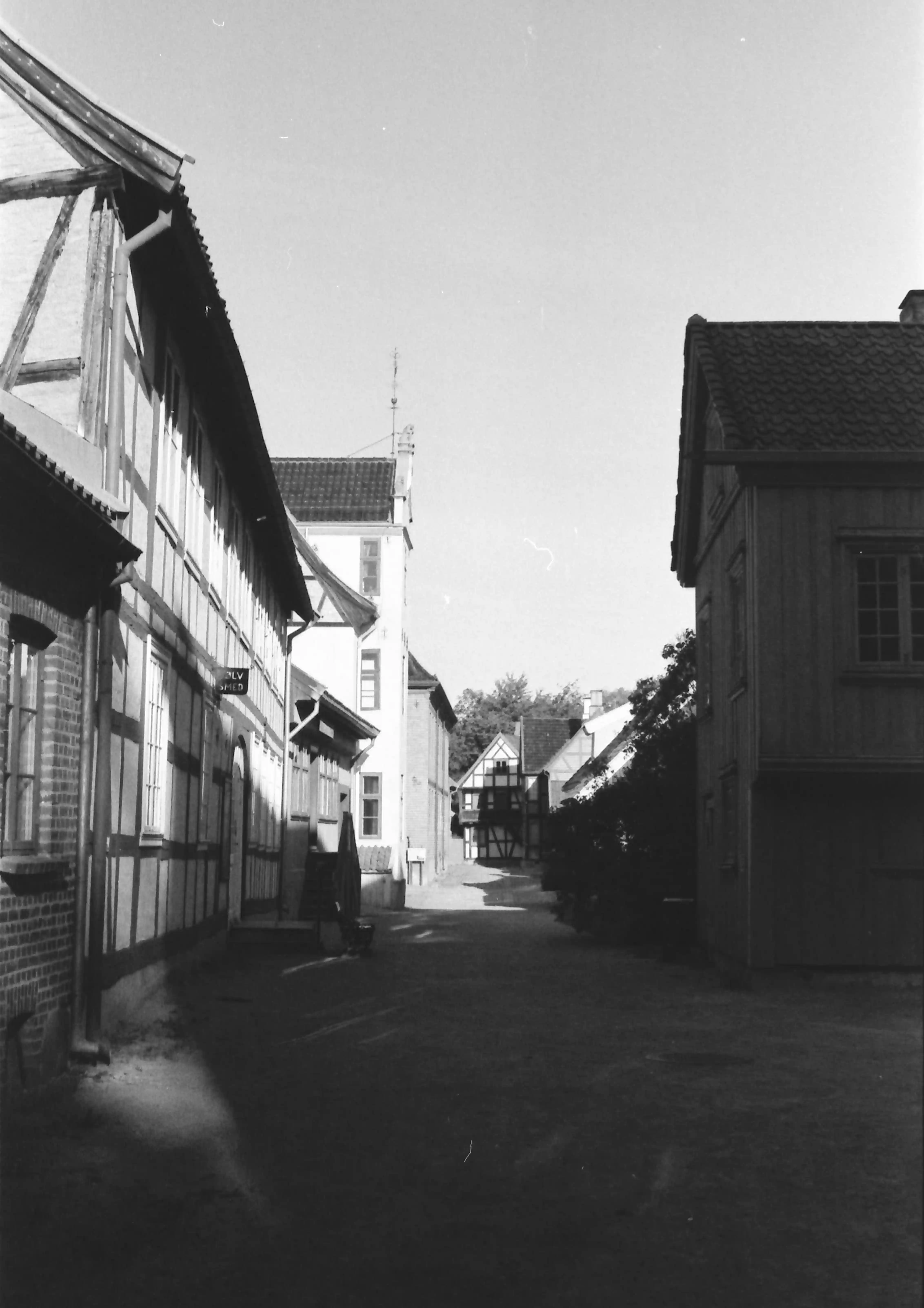 Black and white picture of a street in between historical Norwegian wooden houses